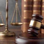 Scales of justice and a gavel with law books in the background.