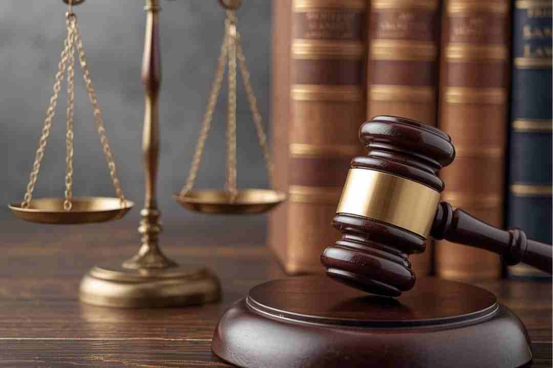 Scales of justice and a gavel with law books in the background.